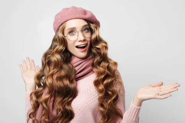 Model wanita muda yang cantik dengan rambut panjang bergelombang mengenakan baret merah muda dan syal — Stok Foto