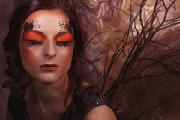 Krása a umění koncept: mladá žena s světlé make-upu s suchých větví — Stock fotografie