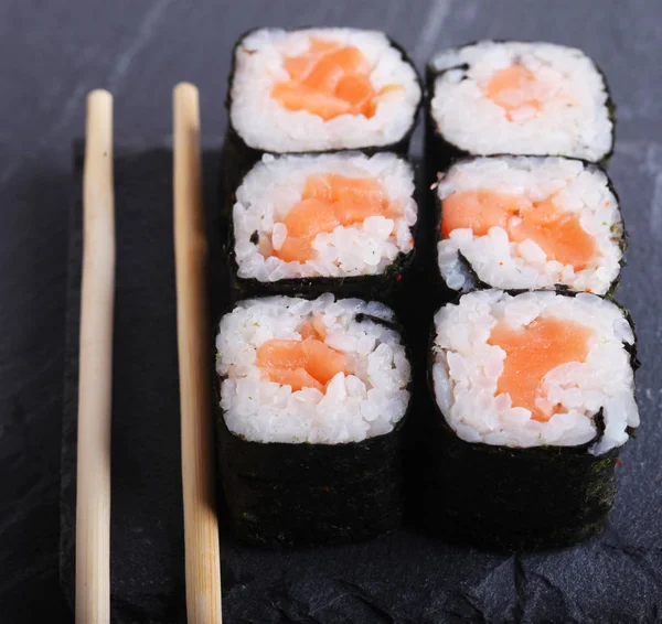 Maki se převaluje s šedým pozadím. Japonské Sushi. Detailní záběr. — Stock fotografie