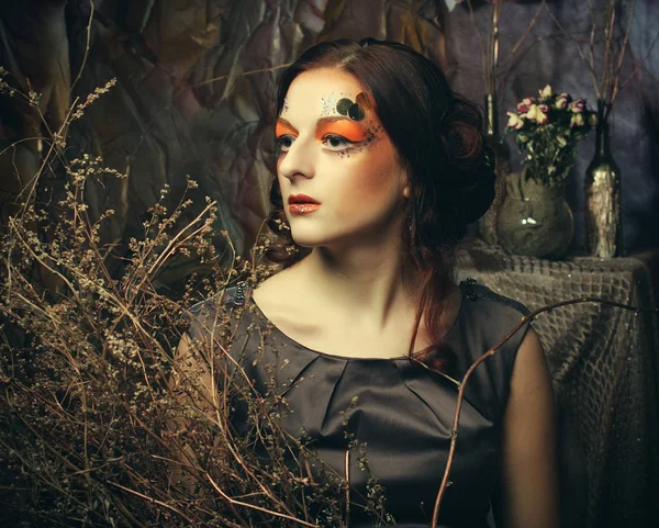 Concepto de belleza y arte: Mujer joven con maquillaje brillante con ramas secas — Foto de Stock