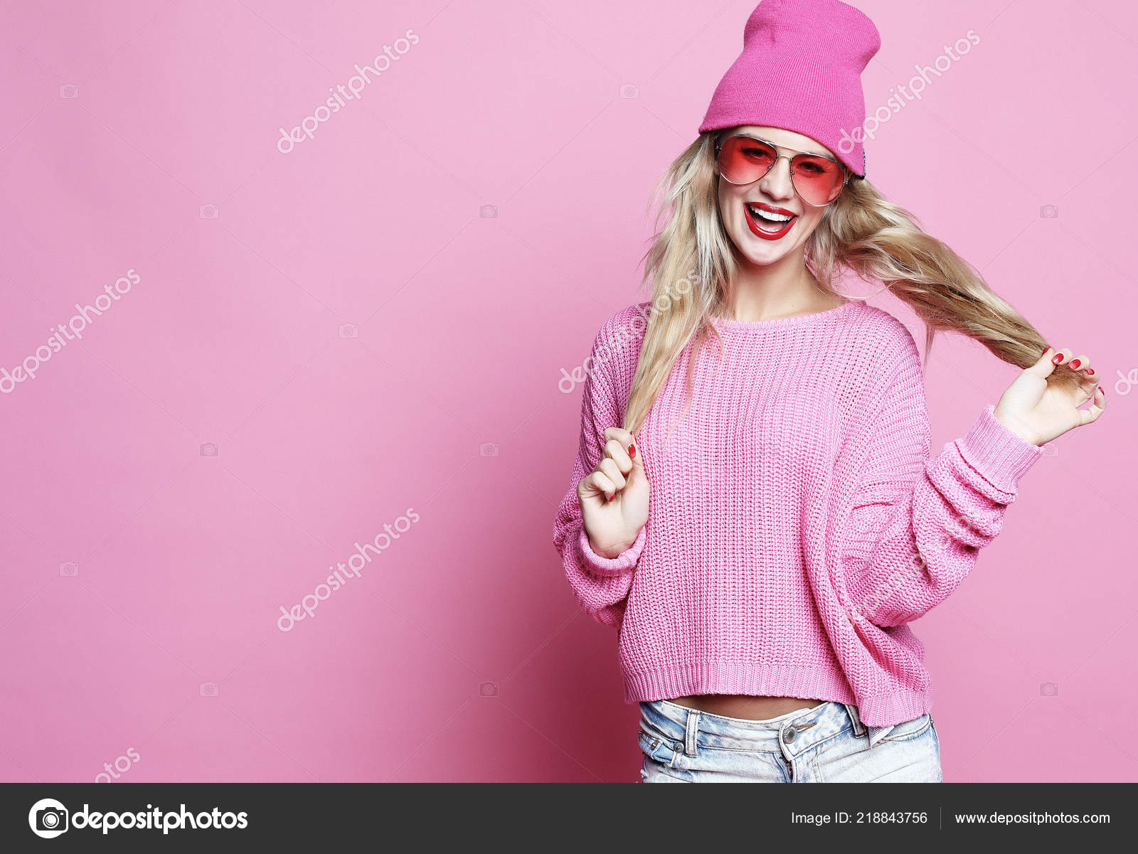 Stylish Fashion Portrait Of Trendy Casual Young Woman In Pink Pulover And Hat Posing Over Pink 
