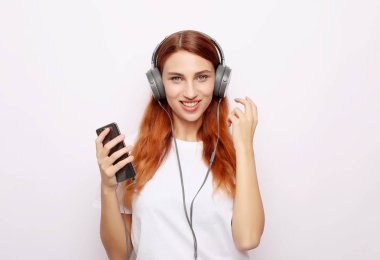 Kulaklıklı, beyaz arka planda müzik dinleyen güzel genç bir kadın.