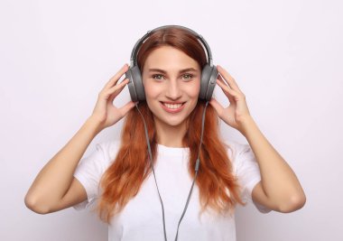 Kulaklıklı, beyaz arka planda müzik dinleyen güzel genç bir kadın.