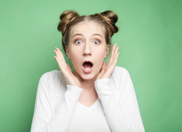 Estilo de vida y el concepto de la gente: Mujer joven sorprendida gritando sobre fondo verde. Mirando la cámara . — Foto de Stock