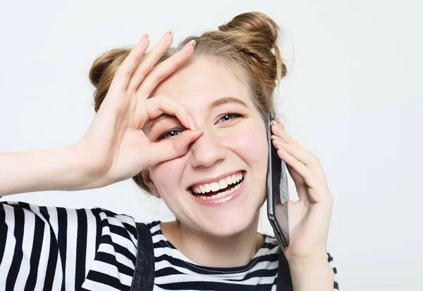 Hermosa mujer alegre sonriendo, demostrando dientes blancos, mirando a la cámara a través de los dedos en buen gesto . — Foto de Stock