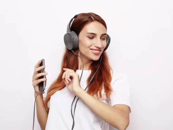 Belle jeune femme dans les écouteurs écoutant de la musique sur fond blanc — Photo