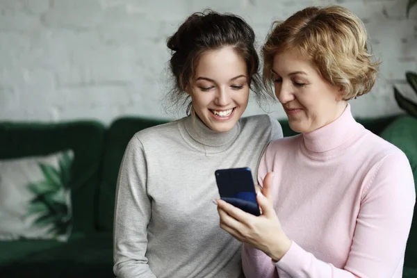 Famiglia, persone e tecnologia. Donna anziana e sua figlia adulta utilizzando smartphone a casa. — Foto Stock