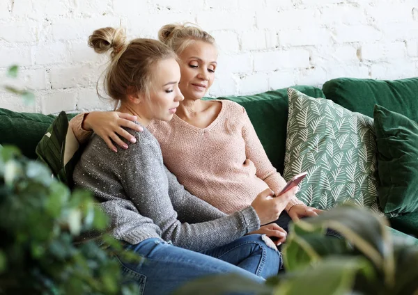 Familj, människor och teknik. Åldrad kvinna och hennes vuxna dotter använder smartphone hemma. — Stockfoto