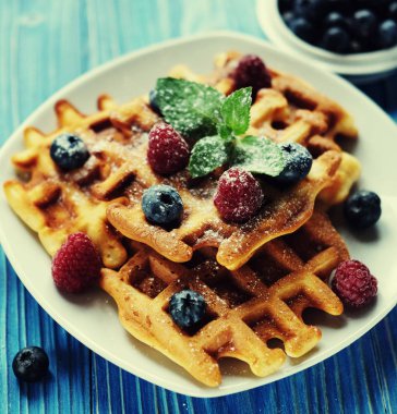 Yaban mersini, ahududu ve ahşap masa üzerine pudra şekeri ile Belçika waffle.