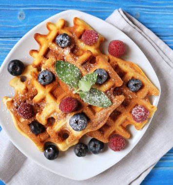 Yaban mersini, ahududu ve ahşap masa üzerine pudra şekeri ile Belçika waffle.