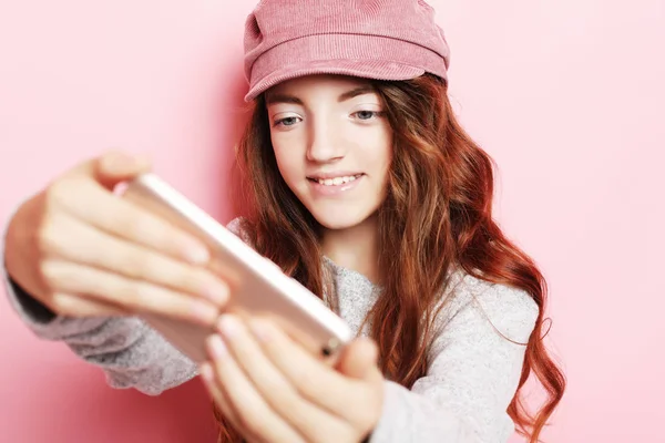 巻き毛 l ピンク背景に分離された selfie を取ると陽気な少女 — ストック写真