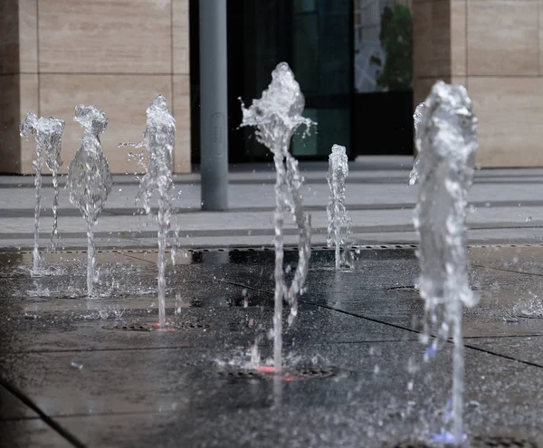 small fountain in the open air, on the street. Drops of water, jets of water frozen in the air in flight against the backdrop.