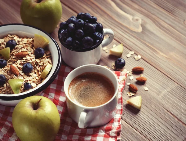 Um café da manhã saudável é um ótimo começo para um novo dia. Mingau de aveia, café, maçã, bagas e nozes em uma mesa de madeira . — Fotografia de Stock