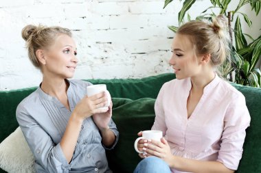 yaşam tarzı ve insanlar kavramı: iki güzel kadın-anne ve kızı evde kanepede oturan. Onlar kahve çay. İlişkiler ve paylaşılan zaman.