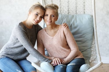 Güzel büyük anne ve yetişkin kızı sarılıyor, kameraya bakıyor ve gülümsüyor..