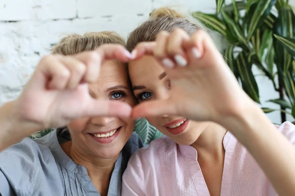 Mother and daughter love. Adult woman and young woman stacking hands in heart sign looking at camera. — Stock Photo, Image