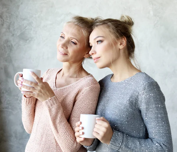 Bella madre matura e sua figlia adulta stanno bevendo caffè, parlando e sorridendo — Foto Stock