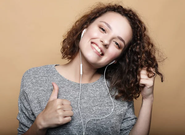 Estilo de vida e conceito de pessoas: mulher encaracolada com polegares para cima ouvir música — Fotografia de Stock