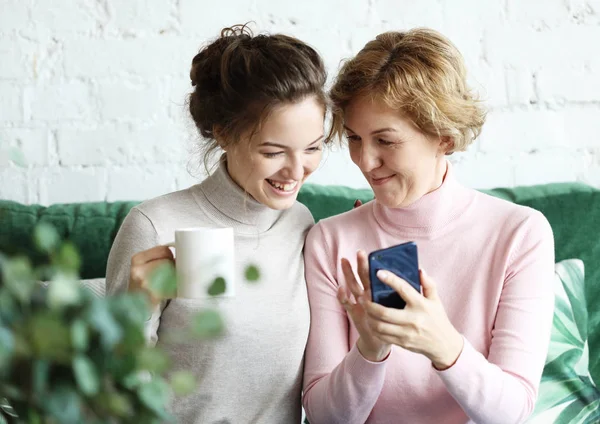 Famiglia, persone e tecnologia. Donna anziana e sua figlia adulta utilizzando smartphone a casa. — Foto Stock