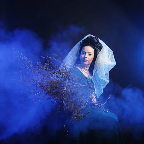 Chica en vestido medieval con montón de palos en el humo — Foto de Stock