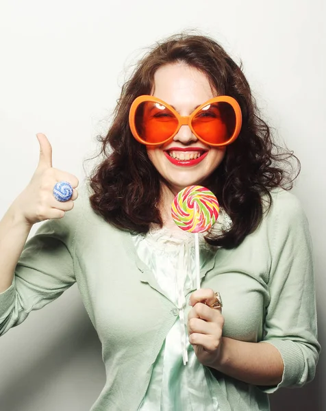 Mujer en grandes gafas de color naranja lamiendo piruleta con su lengua — Foto de Stock