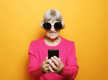 Yaşlı büyükannesi torunlarıyla telefonda konuşuyor, gülümsüyor ve onları selamlıyor..