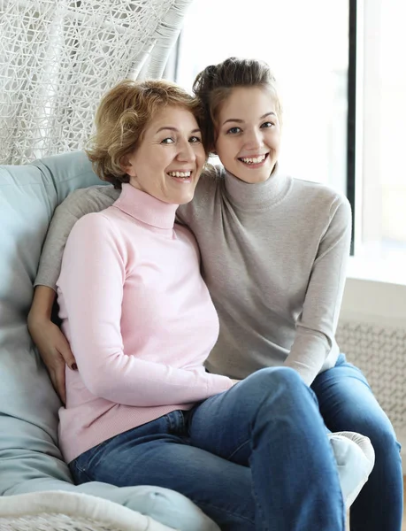 Die schöne Seniorin und ihre erwachsene Tochter umarmen sich, blicken in die Kamera und lächeln. — Stockfoto
