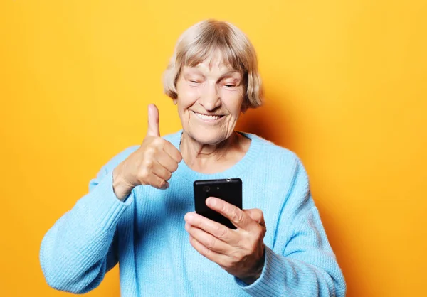 Velha avó está falando com seus netos por telefone, sorrindo e cumprimentando-os. — Fotografia de Stock