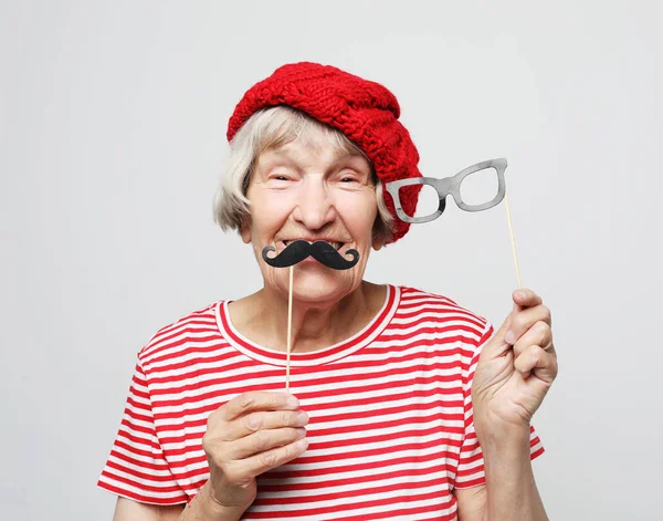 Lifestyle and people concept: funny grandmother with fake mustache and glasses, laughs and prepares for party — Stock Photo, Image