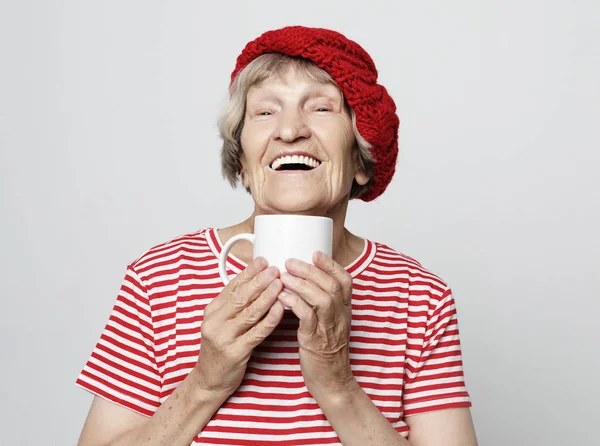 Lifestyle and people concept: old excited lady smiling laughing, holding cup drinking coffee, tea — Stock Photo, Image