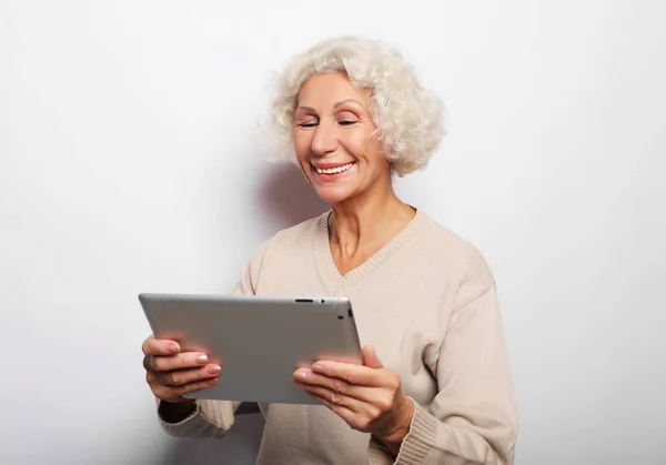 Mulher madura feliz usando um tablet, se comunica com filhos e netos — Fotografia de Stock