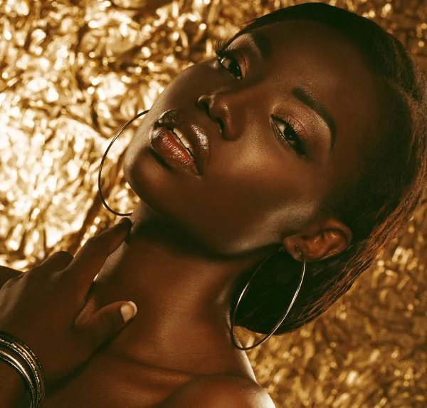 Portret van sensuele jonge Afrikaanse vrouw tegen gouden achtergrond — Stockfoto