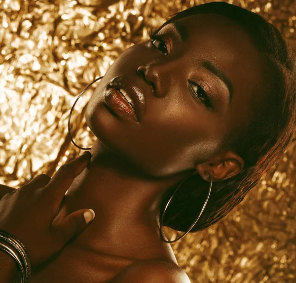 Retrato de sensual jovem mulher africana contra fundo dourado — Fotografia de Stock