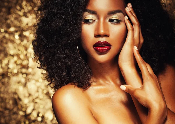 Joven elegante mujer afroamericana con pelo afro. Maquillaje de glamour. Fondo dorado . — Foto de Stock