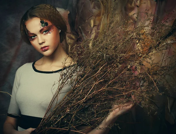 Красота и художественная концепция: молодая женщина с ярким макияжем с сухими ветвями — стоковое фото