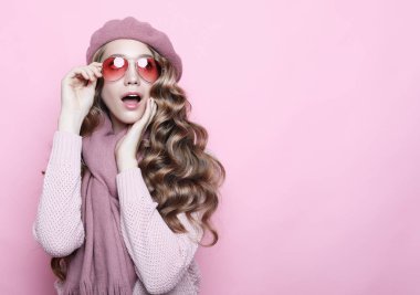 Genç kadın modeli uzun dalgalı saçlı pembe bere, eşarp ve gözlük, yakın çekim