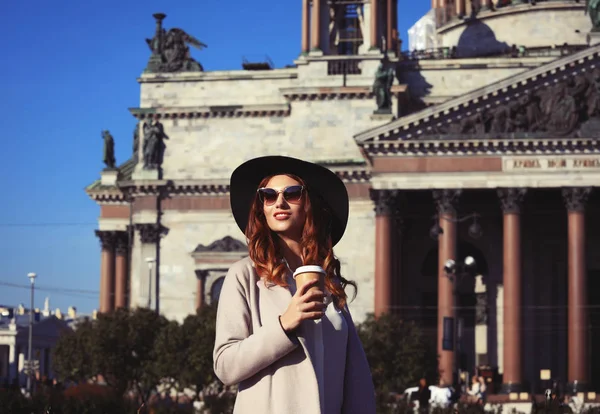 Sorridente elegante giovane donna bere caffè mentre si cammina su un c — Foto Stock