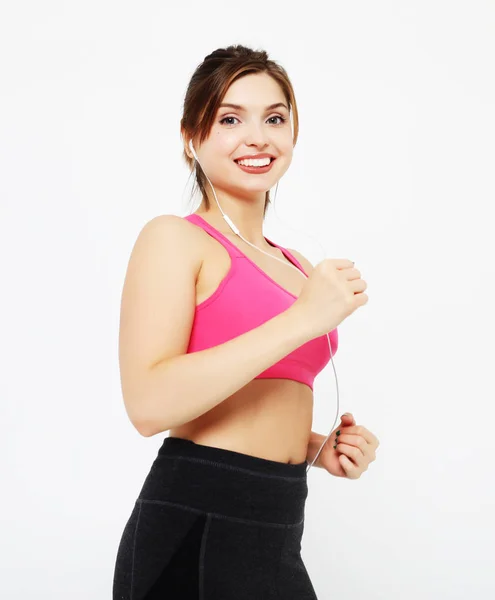 Portrait of a smiling fitness woman in headphones working out isolated over white background — Stock Photo, Image