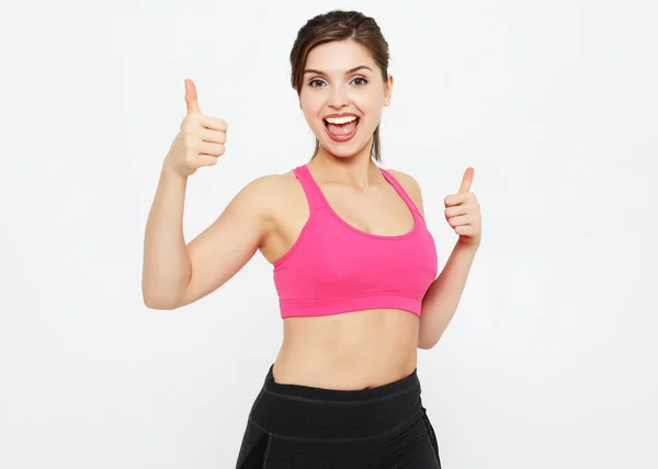 Beyaz bir arka plan üzerinde izole ok işaret gösteren bir genç fitness kadın portresi — Stok fotoğraf
