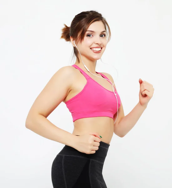 Porträtt av en leende fitness kvinna i hörlurar träna isolerad över vit bakgrund — Stockfoto