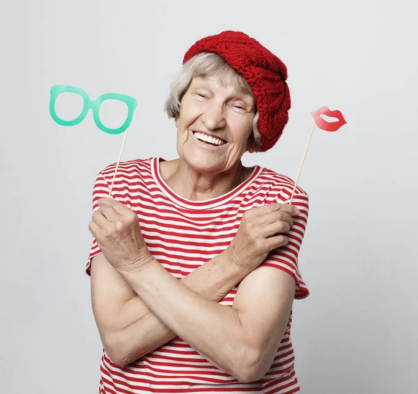 Funny grandmother wearing red clothes holding falce glasses and ready for party — Stock Photo, Image