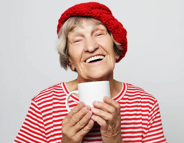 Koncepcja życia i ludzi: staruszka podekscytowany, uśmiechając się, śmiejąc się, gospodarstwa kubek do picia kawy, herbaty, napojów — Zdjęcie stockowe