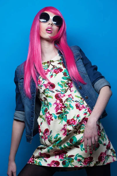 Fashion model with pink hair and big sunglasses over blue  background — Stock Photo, Image