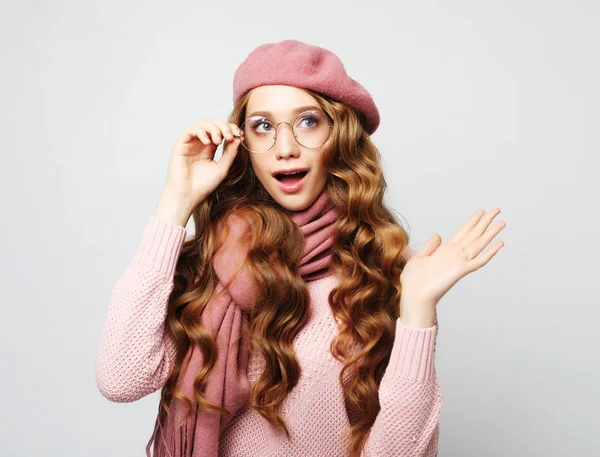 Gyönyörű fiatal női modell hosszú hullámos hajjal rózsaszín svájcisapkát, sálat és szemüveget visel — Stock Fotó