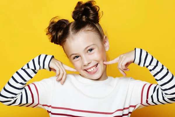 Портрет веселой улыбающейся маленькой девочки на желтом фоне — стоковое фото