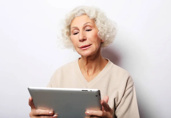 Mulher madura feliz usando um tablet, se comunica com filhos e netos — Fotografia de Stock