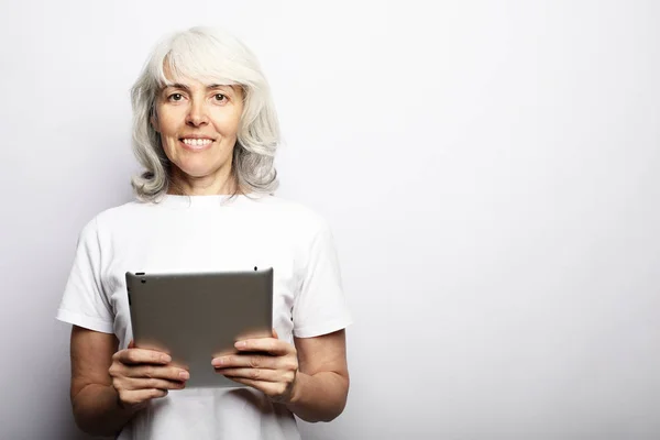 Старшая счастливая женщина, используя ipad изолированы на белом фоне — стоковое фото
