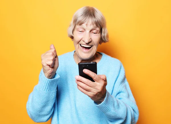 Mulher velha vestindo camisola azul falando no telefone celular — Fotografia de Stock