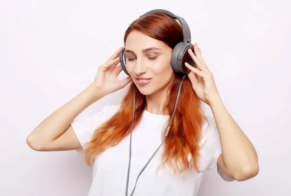 Hermosa pelirroja mujer en auriculares escuchando música —  Fotos de Stock