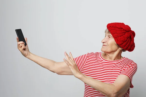 Lifestyle, family and people concept: old grandmother is talking to her grandchildren by phone, smiling and greeting them — Stock Photo, Image